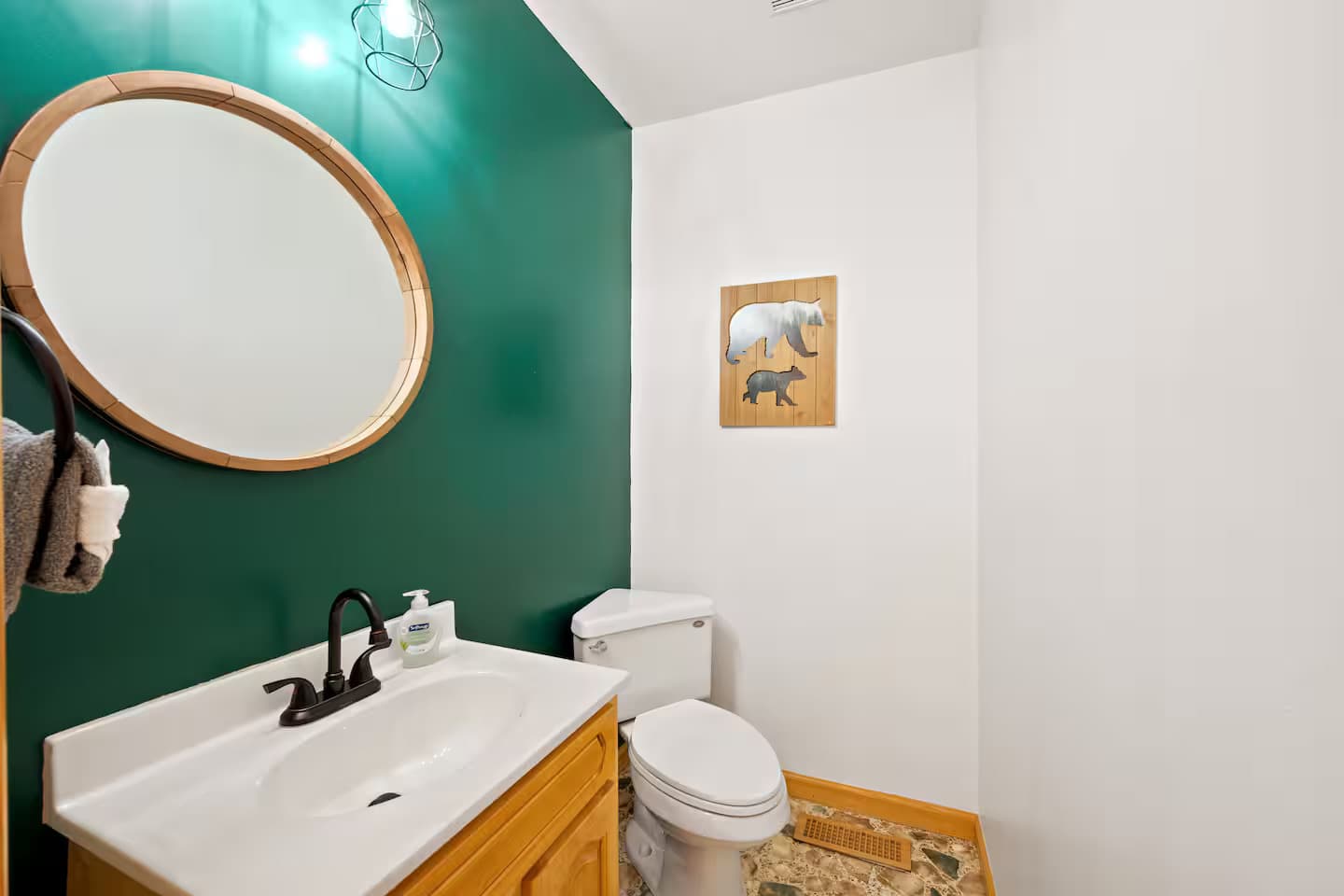A small half-bathroom with a green accent wall and a black-bear silhouette print.