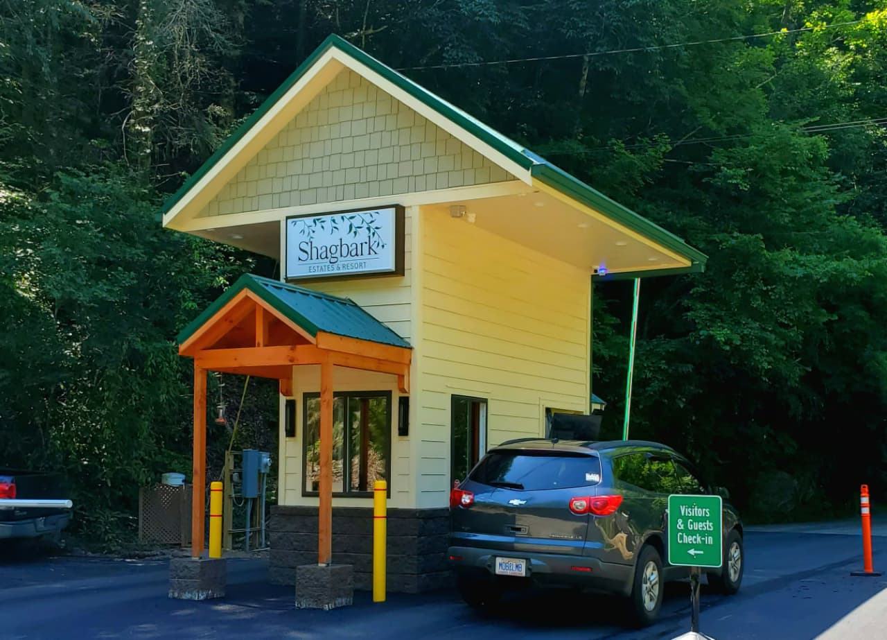The Shagbark resort visitor check-in gatehouse surrounded by dense green trees.
