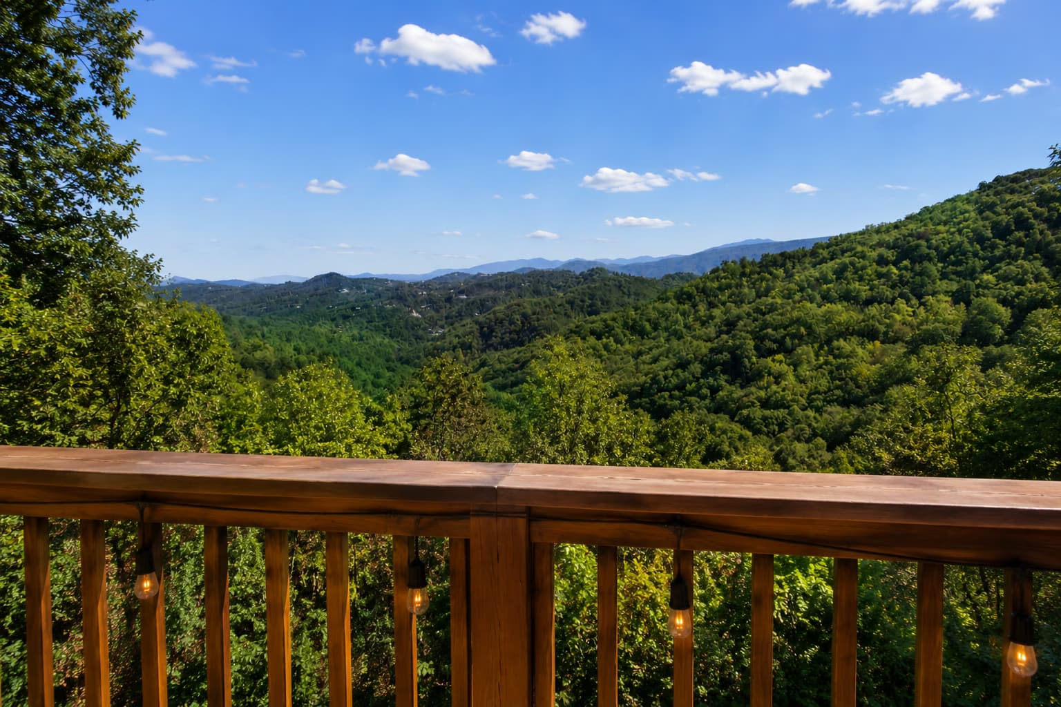 Panoramic view from the cabin deck across green forested ridges beneath a bright blue sky.