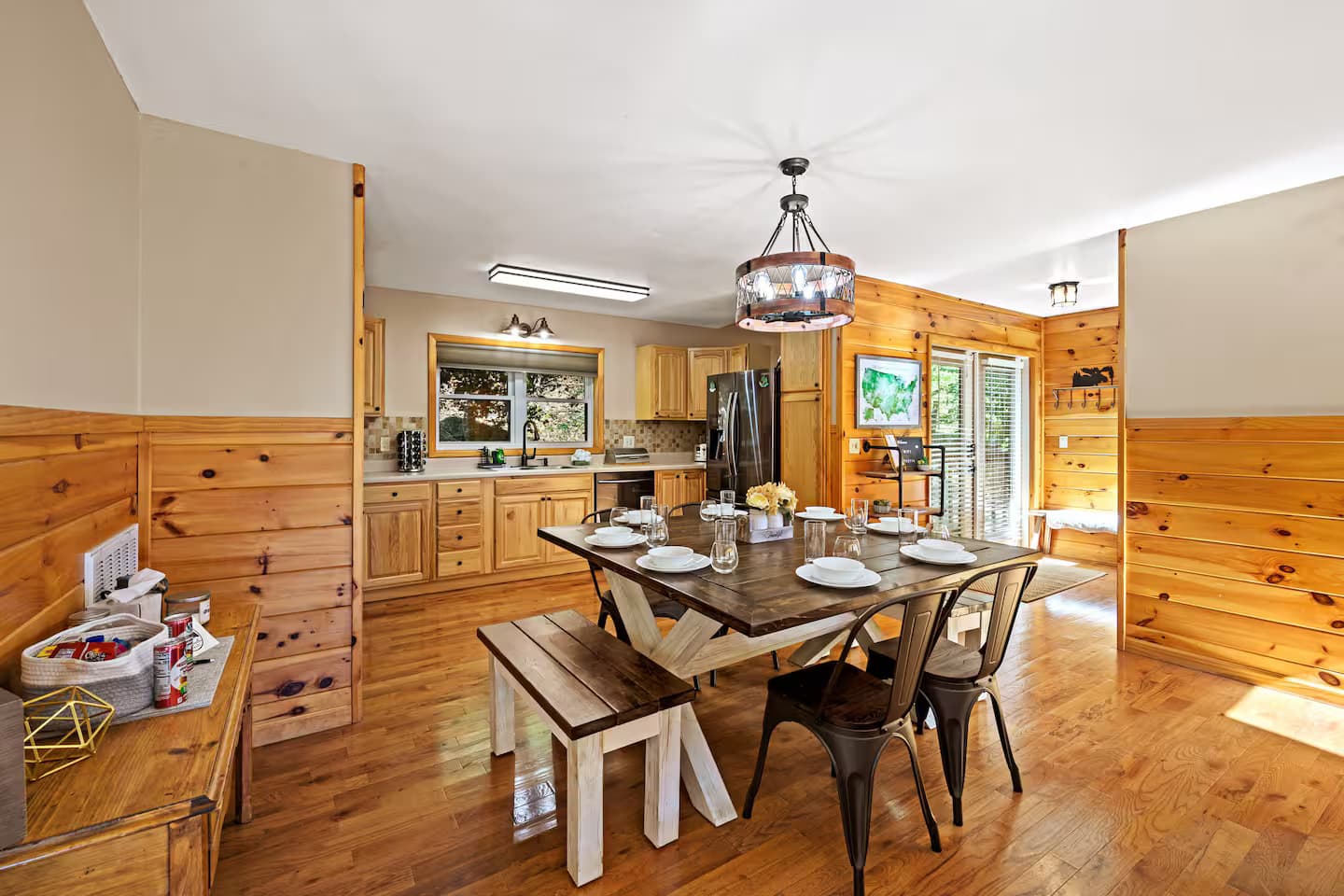 An open-concept kitchen and farmhouse dining table set for six, with a glass door leading to the deck.