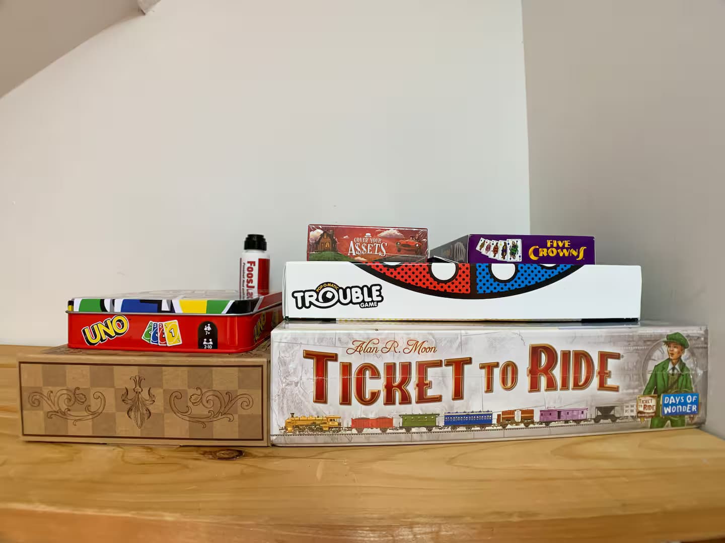 A stack of board games on a wood shelf.