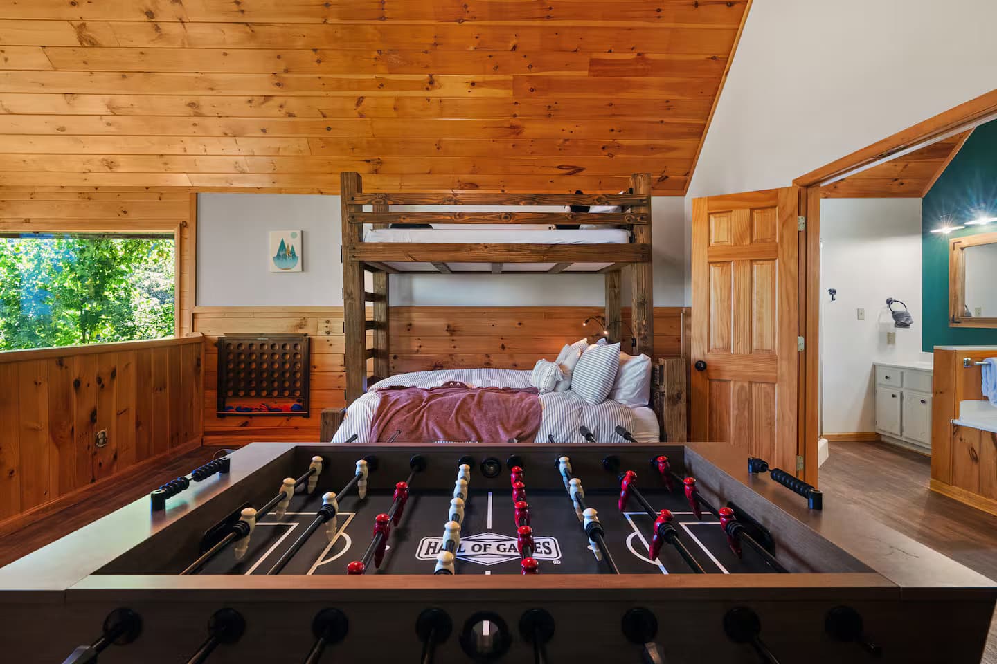 Bunk beds with striped pillows and a foosball table in the foreground.
