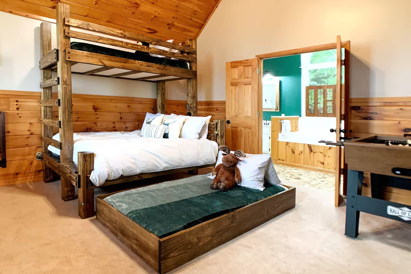 A bunk bed with a trundle and a stuffed moose plush on the pillows.