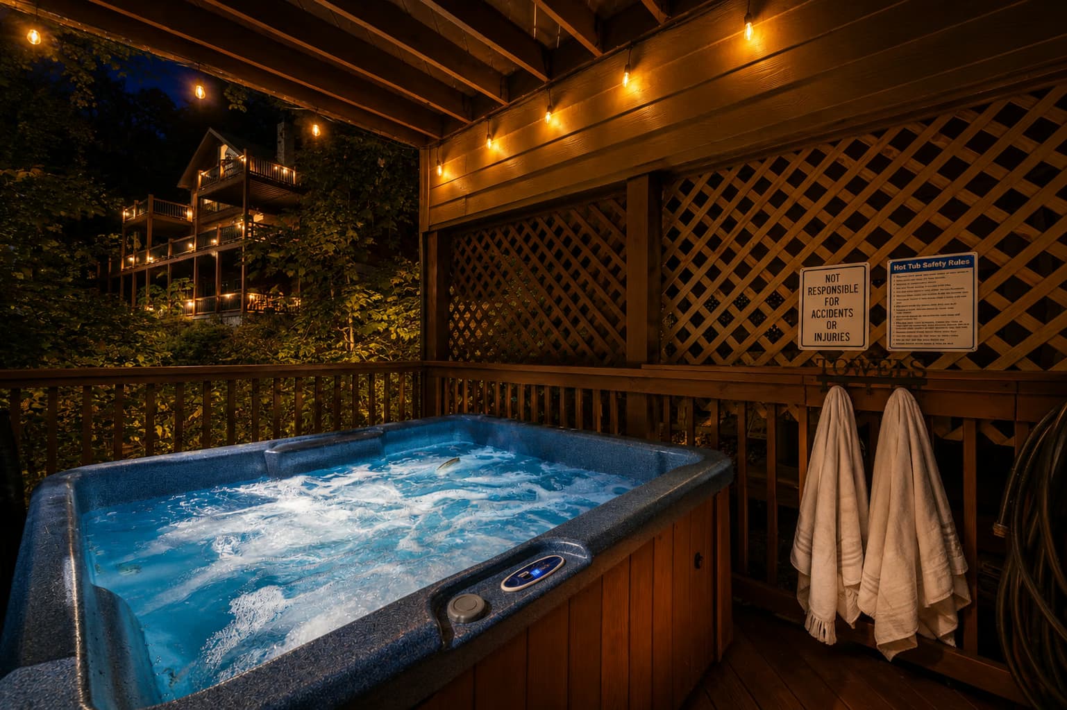 A bubbling hot tub glowing beneath warm string lights on a covered deck at night.